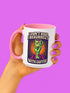 White ceramic coffee mug with red handle and interior, featuring a bold design of a zombie hand holding a coffee cup with the text “I Don’t Rise, I Resurrect With Coffee” in white and purple, accented with a neon green hand and orange sunburst background.