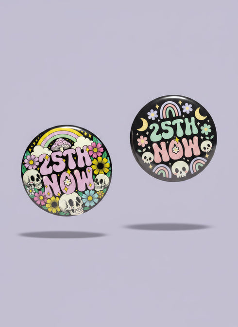 A round pinback button featuring a solid black background covered in a retro pastel colored design. The center reads 25TH NOW in a groovy bubbly font using pale pink and mint green referencing the 25th amendment. Surrounding the text is a maximalist cluster of cute but edgy motifs including smiling white skulls, pastel rainbows, pale yellow crescent moons, daisies, and a pink and white spotted mushroom. The button has a glossy laminate finish and a secure metal safety pin backing.