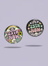 A round pinback button featuring a solid black background covered in a retro pastel colored design. The center reads 25TH NOW in a groovy bubbly font using pale pink and mint green referencing the 25th amendment. Surrounding the text is a maximalist cluster of cute but edgy motifs including smiling white skulls, pastel rainbows, pale yellow crescent moons, daisies, and a pink and white spotted mushroom. The button has a glossy laminate finish and a secure metal safety pin backing.