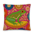 A square decorative throw pillow made from premium polyester with a visible linen-like woven texture. The background is a vibrant hot pink covered in a dense, retro-style floral pattern in orange, teal, and gold. The main design is a brightly colored, stylized illustration of a green red-eyed tree frog with orange feet and prominent red eyes. The whimsical frog is riding a vibrant yellow banana. The overall aesthetic is colorful, maximalist, and eclectic, with a faux-embroidered texture effect.
