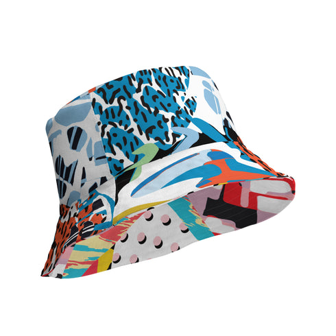 A reversible 90s-inspired bucket hat with two maximalist designs. One side showcases a colorful collage of polka dots and abstract patchwork shapes in vibrant reds, yellows, greens, and blues, evoking a playful retro feel. The opposite side features a contrasting blue-toned leopard print with geometric accents, adding an edgy streetwear flair. The hat has a soft linen-textured polyester fabric that’s lightweight, moisture-wicking, and breathable.