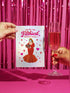 A 5x7 inch pearlescent silver greeting card featuring a flat vector illustration of the drag queen Divine in a red mermaid gown holding a heart-shaped box of chocolates. The text above reads "You're The Filthiest Person Alive" in bold red script with pink sparkles. The card has a shimmering finish that reflects light. Inside text reads "...and I love it." The back features the Honey Dazed logo. Includes a matching envelope.