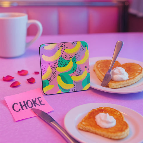 Square drink coaster featuring a playful banana print with bold yellow bananas over a pastel pink, purple, and green abstract background. Made of durable hardboard MDF with a cork backing and a glossy protective topcoat. Measures 3.74 by 3.74 inches, water-repellent and heat-resistant. Perfect for fruit-themed, retro, Y2K, coquette, or dopamine-core decor styles.