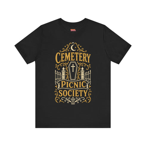A black unisex crewneck graphic t-shirt featuring an ornate Victorian-inspired emblem printed on the chest in vintage gold and off-white. The centralized, symmetrical design showcases a classic coffin with a cross on the lid, flanked by wrought-iron cemetery gates. Beautiful scrollwork and decorative filigree flourishes surround the bold, retro serif text reading CEMETERY PICNIC SOCIETY. A crescent moon and stars sit at the top, completing this gothic memento mori graphic shirt.