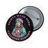 Pinback button badge featuring a saint-inspired roller skater wearing pads and a helmet, with pink hair and teal robes. Surrounded by retro starbursts, the black button reads “Saints Wear Pads Catching Elbows” in pastel pink and teal lettering. Design is bold, colorful, and printed on a glossy metal surface with a classic safety pin back. Available in 2.25" or 3" sizes.