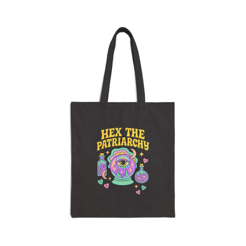 Canvas cotton tote bag with bold “Hex the Patriarchy” design printed on the front, featuring a dripping purple eye in a crystal ball surrounded by pastel potion bottles and hearts. Bag is available in black or natural cotton with long canvas handles.