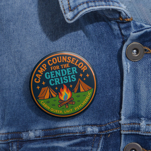 Round glossy pinback button measuring 2.25 inches featuring a playful camp-themed design with the phrase “Camp Counselor for the Gender Crisis.” The artwork includes two orange tents, a rainbow campfire, stars, and green grass. Bottom text reads “Cabin Queer, Unit Psychedelic.” Made from durable tinplate with a safety pin back and coated in a UV and scratch-resistant mylar finish. Bold and colorful, perfect for jackets, bags, or pride outfits.