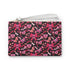 Rectangular wristlet clutch featuring a dark background with pink skull bows, cherries, and other goth-inspired motifs. White strap and gold zipper visible.