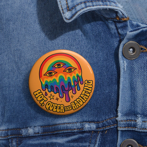 Round orange pinback button featuring bold rainbow psychedelic artwork of a melting third-eye face beneath a rainbow arch. Surrounded by stars and the phrase “Hot, Queer and Radiating” in retro black bubble letters. Glossy metal badge with UV-resistant mylar face and secure safety pin back.