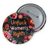 Round pinback button with black background featuring vibrant floral embroidery design surrounding bold orange and white text reading "Unfuck Women's Rights" - feminist protest accessory with glossy finish, safety pin backing, available in 2" and 3" sizes for jackets, bags, and activist wear.