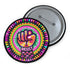 Round pinback button with psychedelic rainbow design featuring a raised black fist surrounded by concentric circles in vibrant pink, orange, green, and yellow. The word "RESIST" appears in white text below the fist, set against black background with flower details. Activist protest pin with glossy finish and safety pin backing.