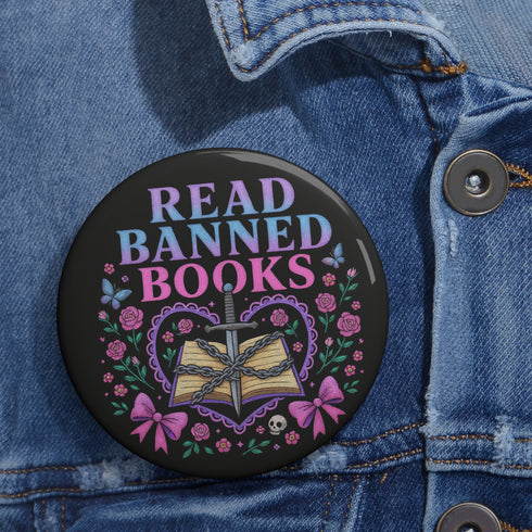 Glossy black pinback button that says “Read Banned Books” in purple and teal letters, featuring a chained book, roses, bows, and floral accents, styled on colorful books and pastel backgrounds.