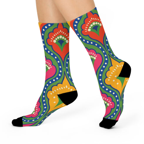 Crew-length socks featuring a vibrant 70s psychedelic pattern on a dark emerald green background. The design consists of vertical symmetrical medallions with hot pink scalloped edges, royal blue interior teardrops, and safety orange accents at the top ribbing. Fine white and light blue pointillist dots outline the major shapes. The heel and toe are solid black and reinforced. The fabric is a smooth. The pattern is maximalist and colorful, showcasing a retro aestheti.