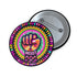 Round pinback button with psychedelic rainbow design featuring a raised black fist surrounded by concentric circles in vibrant pink, orange, green, and yellow. The word "RESIST" appears in white text below the fist, set against black background with flower details. Activist protest pin with glossy finish and safety pin backing.