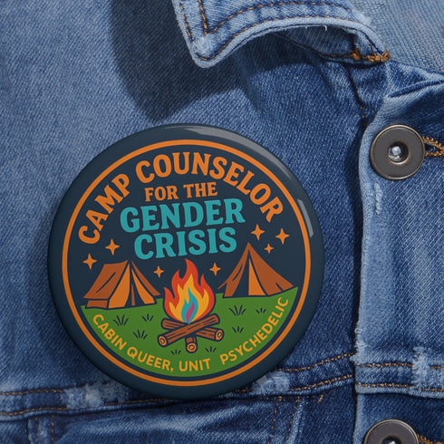 Round glossy pinback button measuring 2.25 inches featuring a playful camp-themed design with the phrase “Camp Counselor for the Gender Crisis.” The artwork includes two orange tents, a rainbow campfire, stars, and green grass. Bottom text reads “Cabin Queer, Unit Psychedelic.” Made from durable tinplate with a safety pin back and coated in a UV and scratch-resistant mylar finish. Bold and colorful, perfect for jackets, bags, or pride outfits.
