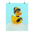 A chic rubber duck styled like Audrey Hepburn’s Holly Golightly, wearing a high bun, yellow bow, black gloves, and a sparkly choker. The duck floats in a pile of foam and is framed in white on a bubbly bathroom shelf with a red tile backdrop and soap dispenser.