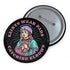 Pinback button badge featuring a saint-inspired roller skater wearing pads and a helmet, with pink hair and teal robes. Surrounded by retro starbursts, the black button reads “Saints Wear Pads Catching Elbows” in pastel pink and teal lettering. Design is bold, colorful, and printed on a glossy metal surface with a classic safety pin back. Available in 2.25" or 3" sizes.