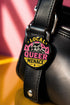 Round pinback button badge with Local Queer Menace text in bold yellow and pink retro lettering on a black background. A cartoon raccoon with a spiked collar flips the middle finger with a painted pink nail, framed by a hot pink sunburst, lightning bolts, and star accents. Glossy laminate finish over durable metal tinplate with a secure safety pin backing. Funny queer pride pin available in 2.25 inch and 3 inch sizes for jackets, totes, lanyards, and backpacks.