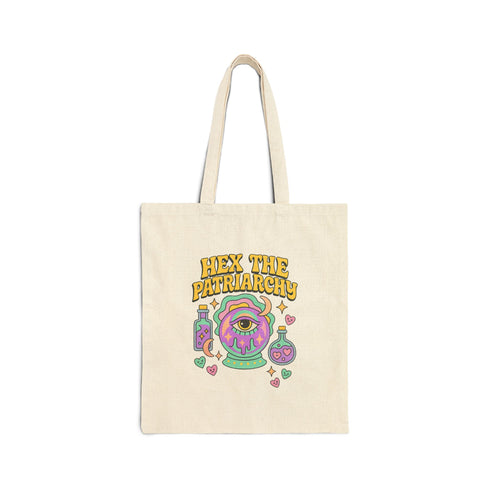 Canvas cotton tote bag with bold “Hex the Patriarchy” design printed on the front, featuring a dripping purple eye in a crystal ball surrounded by pastel potion bottles and hearts. Bag is available in black or natural cotton with long canvas handles.