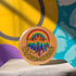 Round orange pinback button featuring bold rainbow psychedelic artwork of a melting third-eye face beneath a rainbow arch. Surrounded by stars and the phrase “Hot, Queer and Radiating” in retro black bubble letters. Glossy metal badge with UV-resistant mylar face and secure safety pin back.