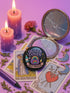 Glossy black pinback button with pastel artwork of a bubbling cauldron, rainbow, potion bottles, and tools. Text reads “Queer Coven, Hex Proud.”