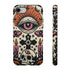 A vertical phone case design featuring a faux crochet texture illusion printed on a cream background. The symmetrical pattern centers on a large black eye with a pink iris and rust-orange sunburst lashes at the top. Below the eye is a black cross surrounded by small black stars. The bottom features a skull with a third rust-orange eye on its forehead. Flanking the skull are two candles with orange flames and rust-colored leaves. The design mimics the look of stitched yarn but is a 2d print.