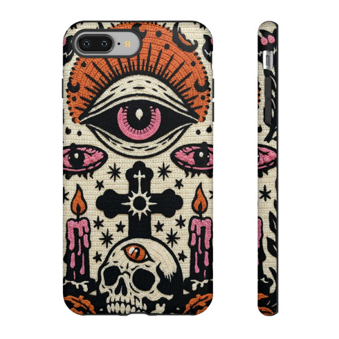 A vertical phone case design featuring a faux crochet texture illusion printed on a cream background. The symmetrical pattern centers on a large black eye with a pink iris and rust-orange sunburst lashes at the top. Below the eye is a black cross surrounded by small black stars. The bottom features a skull with a third rust-orange eye on its forehead. Flanking the skull are two candles with orange flames and rust-colored leaves. The design mimics the look of stitched yarn but is a 2d print.