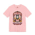A short sleeve unisex crewneck t-shirt featuring a vintage style emblem graphic centered on the chest. The design features a red banner reading BAKE SALE above a black guillotine. Two crossed wooden rolling pins sit below the guillotine, above a layered pink and white cake with a cherry. The graphic is flanked by pink flowers, cherries, and stacks of gold coins. A bottom banner reads FOR THE GUILLOTINE FUND EST. WHENEVER THEY GOT TOO GREEDY. The shirt comes in light pink, cream, and blue.