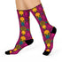 Colorful pink tiger print crew socks with black heel and toe, featuring yellow zebra stripes and teal and coral fan-shaped accents. Made of stretchy knit with a bold maximalist aesthetic. One size fits most, mid-calf length, vibrant all-over print