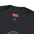 A black unisex crewneck graphic t-shirt featuring an ornate Victorian-inspired emblem printed on the chest in vintage gold and off-white. The centralized, symmetrical design showcases a classic coffin with a cross on the lid, flanked by wrought-iron cemetery gates. Beautiful scrollwork and decorative filigree flourishes surround the bold, retro serif text reading CEMETERY PICNIC SOCIETY. A crescent moon and stars sit at the top, completing this gothic memento mori graphic shirt.