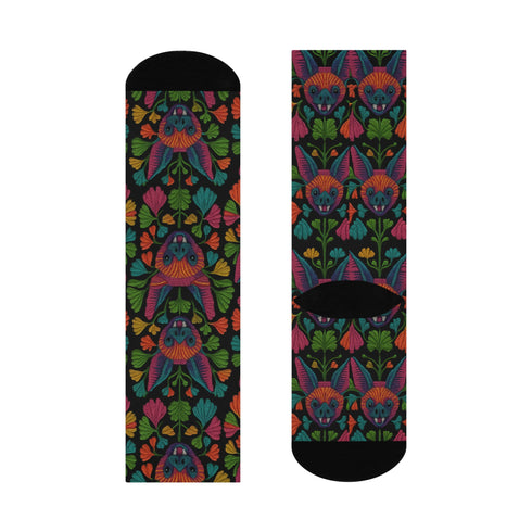 Colorful mid-calf socks with a black background featuring a whimsical folk-art bat pattern in rainbow tones of pink, orange, teal, and green, paired with matching heels and toes.