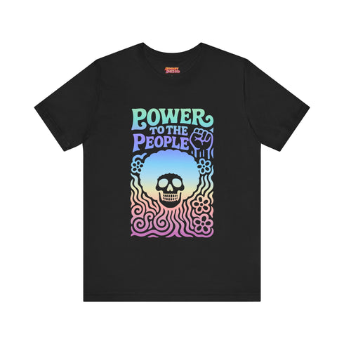 A detailed view of a black unisex graphic t-shirt made of soft cotton, shown flat. The shirt features a large, rectangular design on the chest inspired by 70s psychedelic protest art. The words "POWER TO THE PEOPLE" are printed at the top in a thick, rounded, groovy font. Below the text is a stylized human skull with a large, perfectly round afro hairstyle. The entire design, including the text, skull, and afro, is filled with a vibrant color gradient that shifts from deep purple to hot pink.