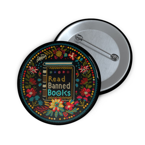 Round black pinback button with vibrant Mexican folk art-inspired embroidery design featuring red, yellow, blue and teal flowers surrounding a gold book spine with "Read Banned Books" text. Literary protest accessory with glossy finish and safety pin backing, available in 2" and 3" sizes.