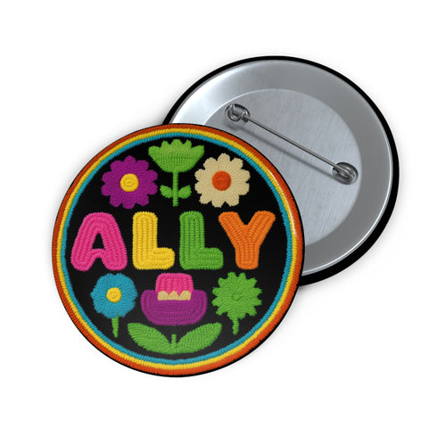 Vibrant ALLY pinback button featuring 70s-style embroidered flowers and lettering in pink, yellow, green, and blue against a black background, surrounded by a rainbow border. A colorful statement accessory combining punk activism and retro flower power aesthetics for backpacks, jackets, and protest wear.