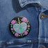 Glossy black pinback button featuring embroidered-style artwork of a pastel purple heart that reads “Read or Die” pierced by a sword and surrounded by roses; shown on books, graffiti, and lace backgrounds.