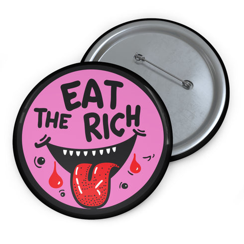 Round pink pinback button featuring a cartoon-style open mouth with sharp teeth, a red tongue, and dripping red details. The bold black text reads “EAT THE RICH” in a hand-drawn style. Glossy black rim with a vibrant, rebellious graphic design.