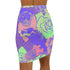High-waisted bodycon mini skirt with a bold floral collage print in green, purple, and pink. Features comic-style roses and dot patterns on stretchy polyester-spandex fabric. Styled for festivals and summer parties. Available in sizes XS to XL.