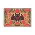 A rectangular beige doormat featuring a large, symmetrical folk art bat illustration in the center. The bat is black with coral red and mustard gold details that mimic the look of satin stitch embroidery. Surrounding the bat are stylized floral motifs in deep pink, coral, and olive green, arranged in a dense, decorative pattern. The texture visually resembles woven linen but is a smooth, flat print. The mat has a solid black trim border and is shown on a flat surface.