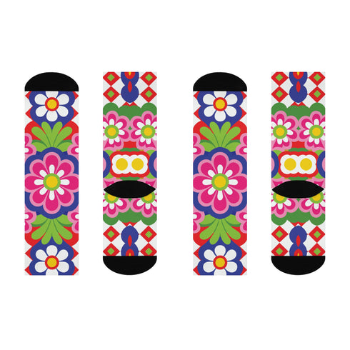 Mid-calf crew sock with a bold 70s psychedelic floral print. The design mixes a red and white diagonal checkerboard with oversized retro flowers, including white daisies with bright yellow centers and a large hot pink bloom with a white inner layer, set over a royal blue background with green leafy foliage. The toe and heel are solid black. The fabric is a soft, stretchy printed knit, made as a one-size unisex statement sock for maximalist and dopamine dressing looks.