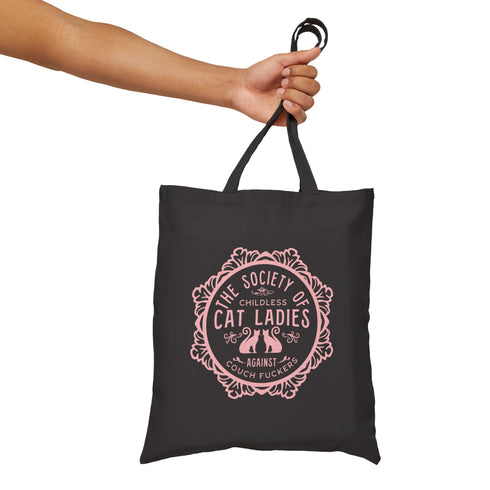 Election 2024 Canvas tote bag featuring a circular design with two cats and text "The Society of Childless Cat Ladies Against Couch Fuckers" in burgundy on a natural or black.