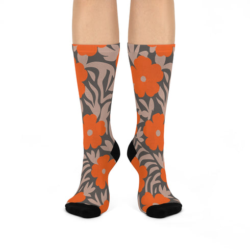 Colorful mid-calf crew socks featuring a bold orange hibiscus floral pattern layered over wavy zebra stripes in taupe and gray, with black heels and toes.