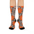 Colorful mid-calf crew socks featuring a bold orange hibiscus floral pattern layered over wavy zebra stripes in taupe and gray, with black heels and toes.