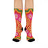 A pair of vibrant crew socks featuring a maximalist 1970s inspired collage pattern. The design includes blocks of hot pink with white daisy flowers and yellow centers, clashing playfully with panels of mustard yellow and orange tiger stripes. Wavy psychedelic lines in grass green and orange frame the top cuff. The socks have a solid black heel and toe cap. The fabric is a smooth, stretchy polyester blend with a flat knit texture and bright colors.