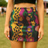 A woman wearing a colorful, patterned mini skirt stands in a grassy field.