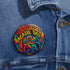 Round glossy pinback button measuring 2.25 inches featuring a vibrant rainbow psychedelic swirl with retro-style text that reads “Psychedelics Made Me Gay.” The background is a mix of rainbow waves and sparkles, with bold, colorful typography in orange, yellow, and blue. Made from durable tinplate with a safety pin backing, scratch-resistant mylar coating, and a high-gloss finish. Ideal for jackets, backpacks, or pride festival accessories.