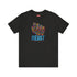 Black t-shirt with vibrant multicolored patterned raised fist graphic and blue "RESIST" text underneath. Rainbow activist protest shirt with psychedelic design elements on cotton-polyester blend.