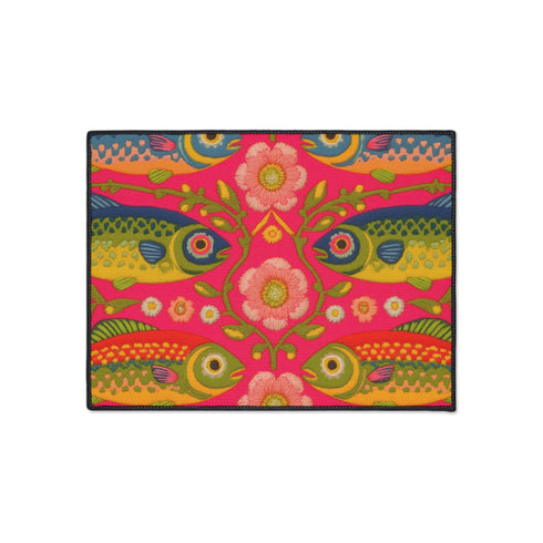 Rectangular indoor outdoor doormat featuring a vibrant hot pink background with a symmetrical maximalist pattern. The design showcases stylized sardines in yellow, lime green, and cobalt blue swimming horizontally towards a central vertical axis of blooming pale pink flowers and green vines. The imagery mimics the texture of vintage needlepoint embroidery but is a flat print on polyester. The mat is framed by a sleek black trim and features a non-slip rubber backing for safety.