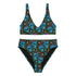 High-waisted bikini set featuring an all-over pattern of neon blue skulls with pink bows, pastel stars, and purple cherries on a dark olive green background. The top has a scoop neckline with wide straps, and the bottoms offer full coverage. A bold, punk-inspired swim look perfect for alternative fashion lovers and dopamine dressers.