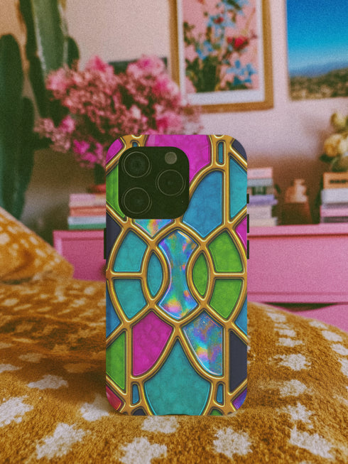 a colorful, patterned phone case with a vibrant design on a bed with a floral pattern.