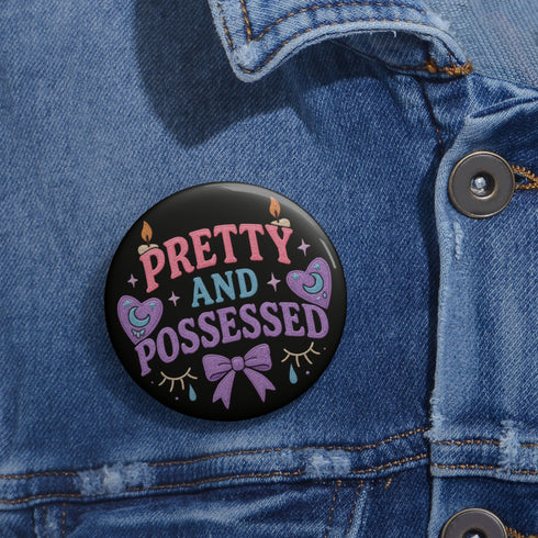 Glossy black pinback button featuring pastel-style text that reads “Pretty and Possessed” with a bow, candles, hearts, and sparkles.
